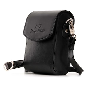 May include: Black leather camera bag with an adjustable strap and a silver clasp. The bag has a flap with a small pocket and the text "MegaGear" embossed on it.