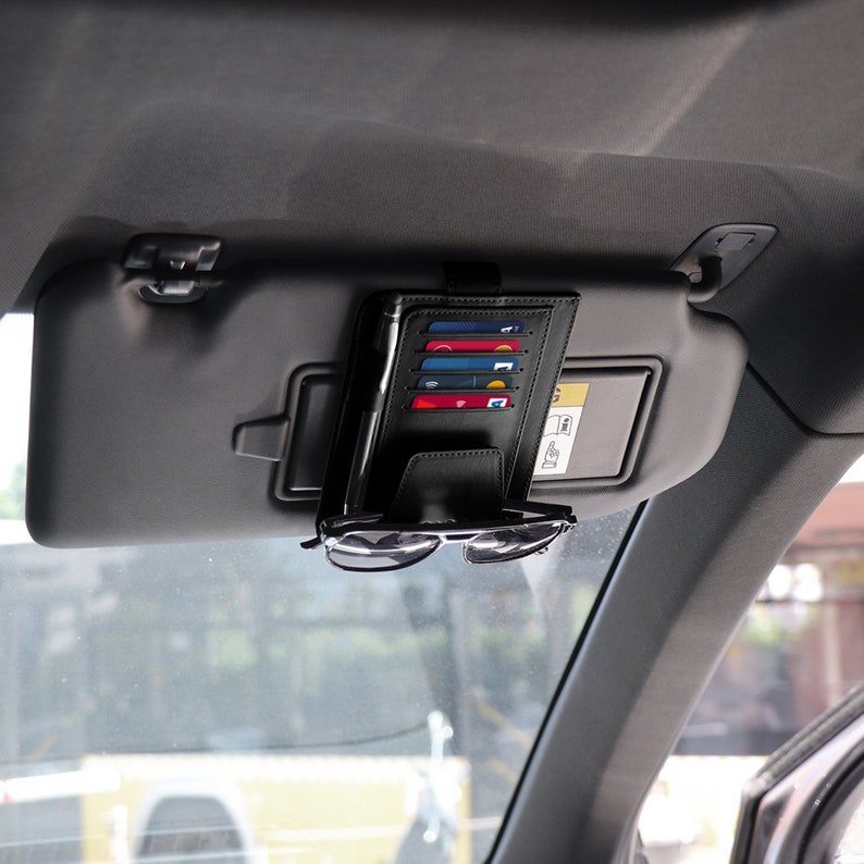 May include: Black leather car visor organizer with slots for credit cards and a clip for sunglasses.