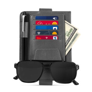 May include: A gray leather wallet with a pen, credit cards, and cash. The wallet has a built-in sunglasses holder and a black pair of sunglasses.
