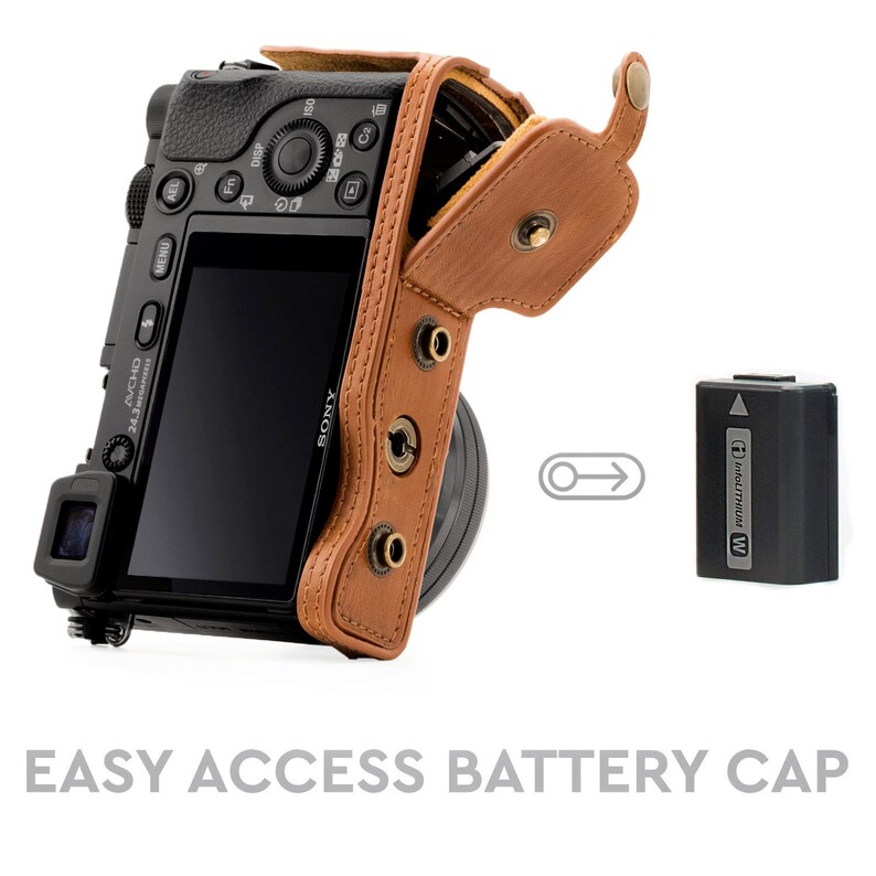Pu&ograve; includere: Una custodia per fotocamera in pelle marrone con una patta che si apre per rivelare una fotocamera nera con un obiettivo. La custodia ha una tracolla e uno scomparto per batterie con una batteria etichettata "InfoLITHIUM W".