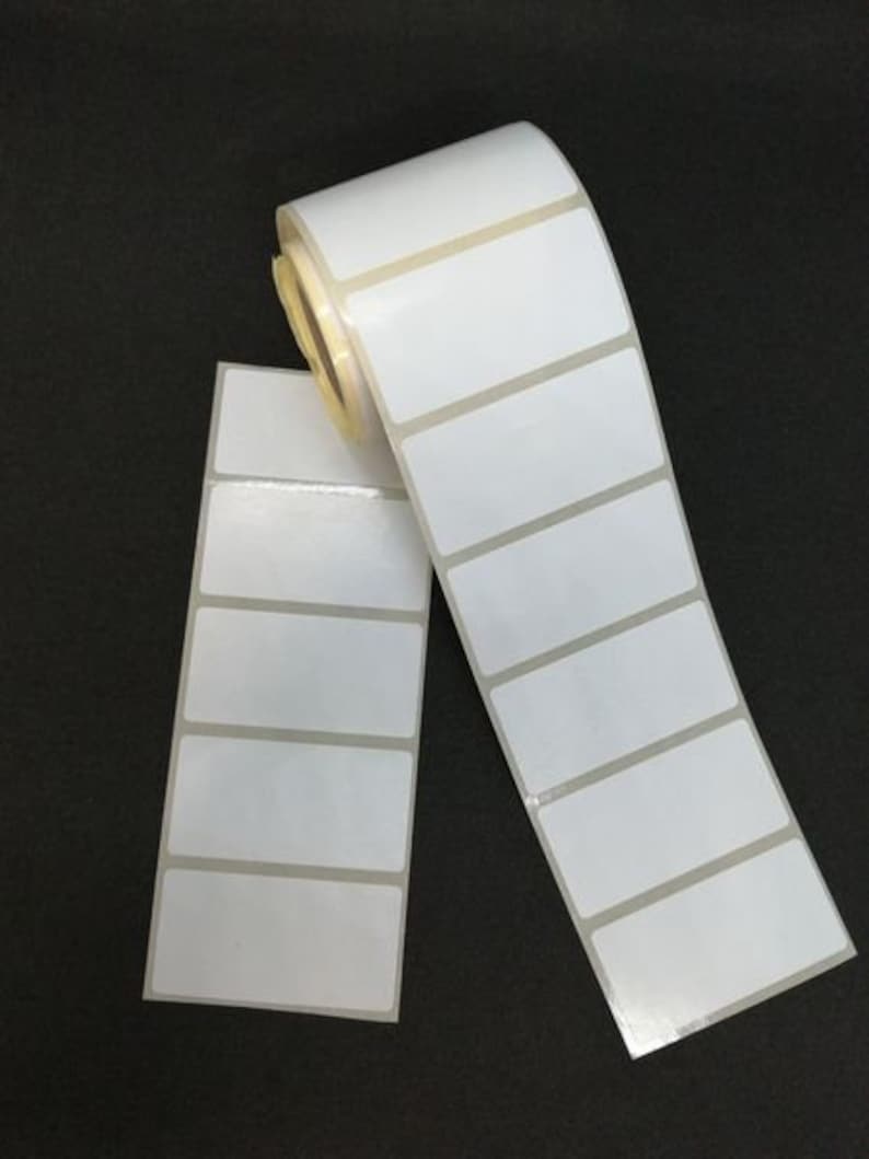 May include: A roll of white adhesive labels with rectangular shapes. The labels are arranged in rows and columns, and the roll is partially unrolled.