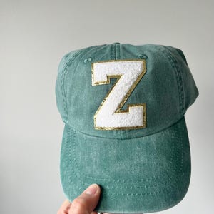 May include: A green baseball cap with a white felt letter Z outlined in gold.