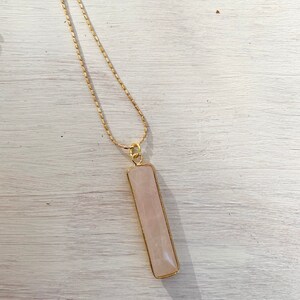 May include: A gold chain necklace with a rectangular pink rose quartz pendant.