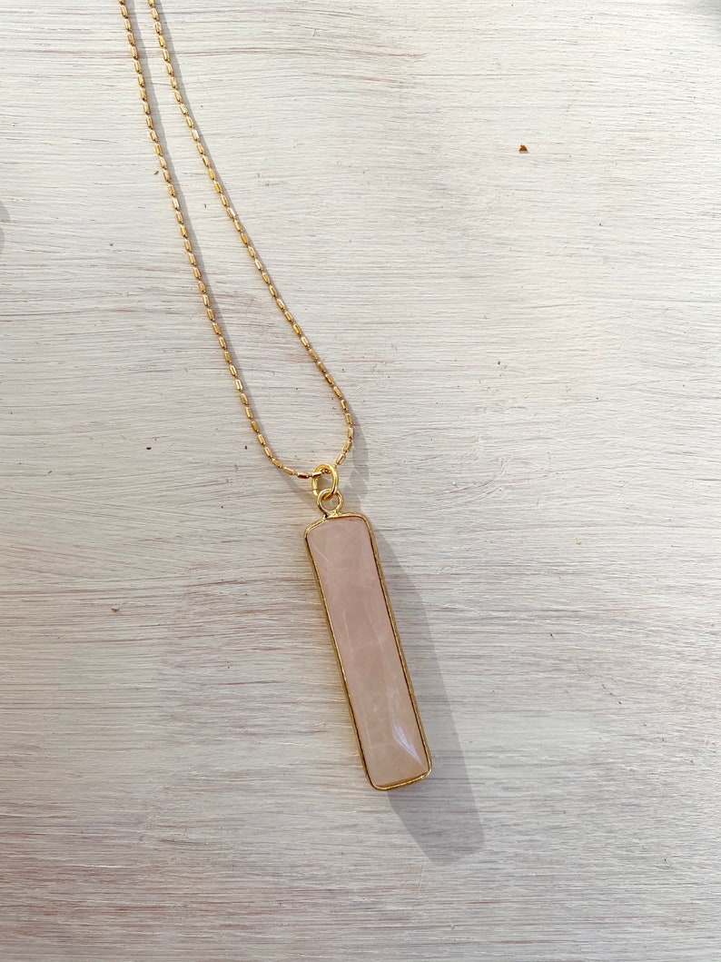 May include: A gold chain necklace with a rectangular pink rose quartz pendant.