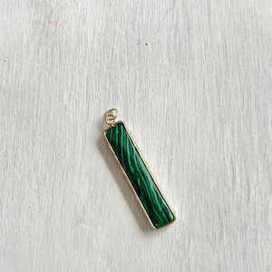 May include: A gold pendant with a rectangular green malachite stone.