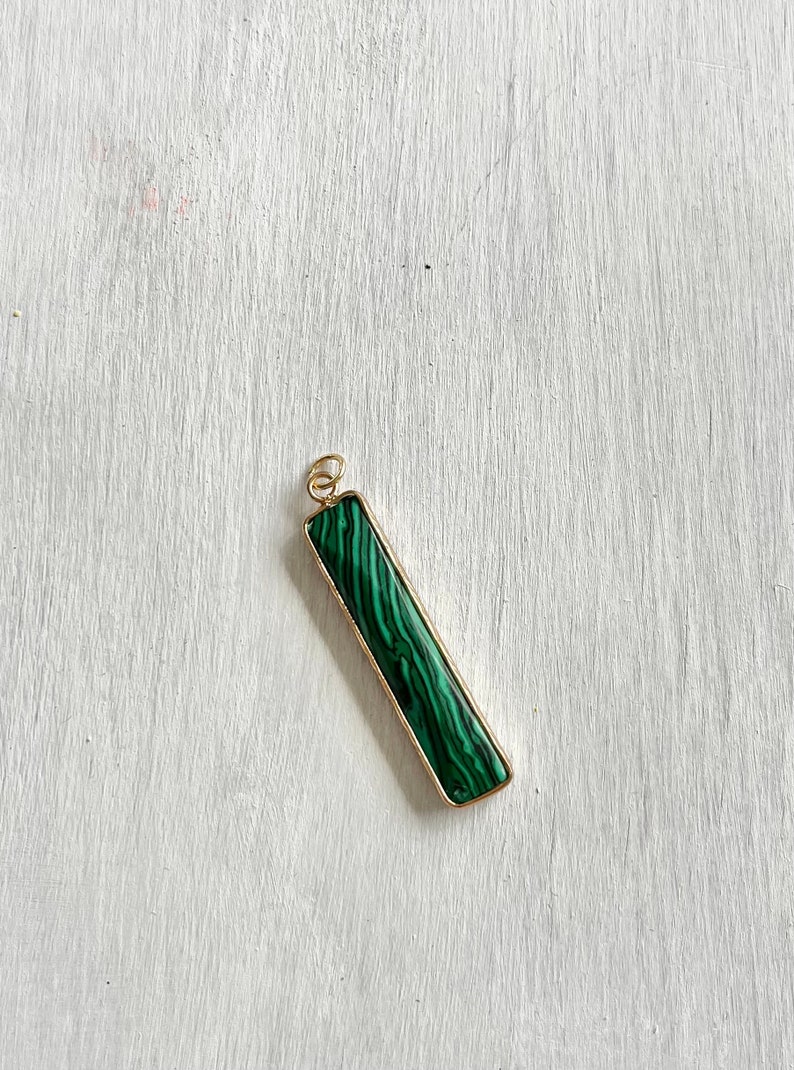 May include: A gold pendant with a rectangular green malachite stone.