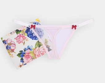 May include: Pink lace thong with red bow accents. The thong is made of a sheer fabric and has a delicate design.