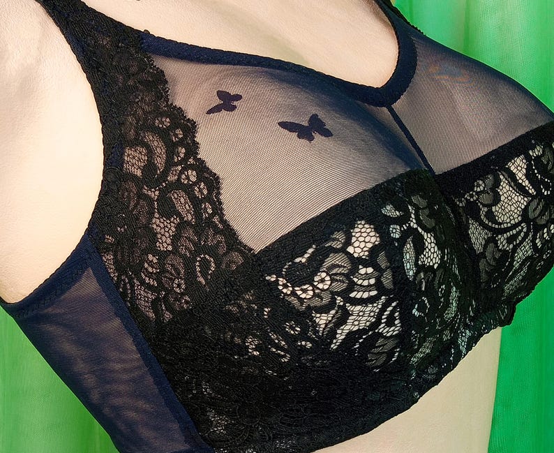 Pode incluir: Suti&atilde; de renda preta com uma sobreposi&ccedil;&atilde;o de tule azul marinho. O suti&atilde; tem um delicado padr&atilde;o floral e um design de borboleta.