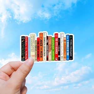 Könnte beinhalten: Ein Aufkleber mit einer Reihe bunter Buchrücken, deren Titel unter anderem The Absolutely True Diary of a Part-Time Indian, The Bluest Eye, The Handmaid's Tale, Forever, The Hate U Give, Of Mice and Men, Bridge to Terabithia, 1984, Lawn Boy, The Kite Runner, The Giver, The Color Purple, A Wrinkle in Time und To Kill a Mockingbird lauten.