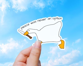 May include: A white goose sticker with an orange beak and orange feet, holding a silver knife in its beak. The text above the goose reads, "peace was never an option" in black, handwritten-style lettering against a white background.