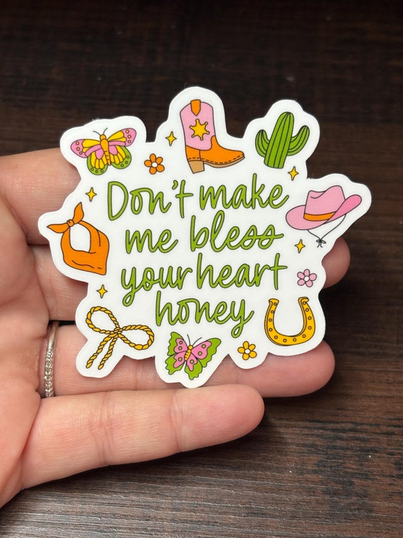 May include: A white sticker with a country theme, featuring a cowboy boot, cactus, horseshoe, and butterfly illustrations. The sticker has the text "Don't make me bless your heart honey" in green script.