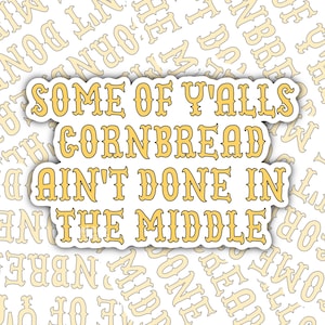 Puede incluir: Una pegatina blanca con el texto "SOME OF Y'ALLS CORNBREAD AIN'T DONE IN THE MIDDLE" en amarillo, con contorno negro. El fondo es un patrón del mismo texto en amarillo pálido.