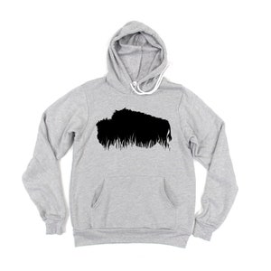May include: A light gray hoodie with a black graphic of a bison. The hoodie has a drawstring hood, a front pocket, and long sleeves. The bison graphic is a silhouette with a textured, grassy base.