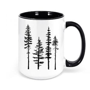 May include: White ceramic mug with a black interior and handle. The mug features a black silhouette of four pine trees on a white background.