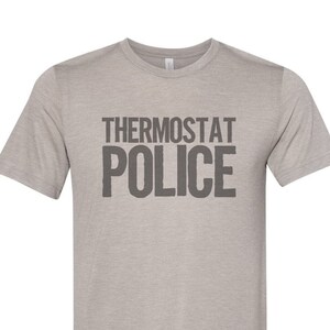 May include: A heather grey t-shirt with the text "THERMOSTAT POLICE" printed in black.