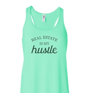 May include: A light green tank top with the text "Real Estate is my hustle" in black.