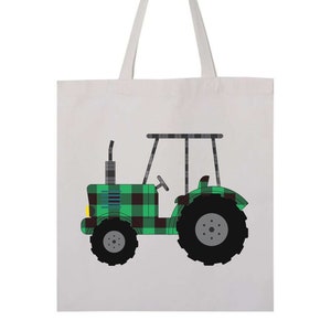 May include: A white canvas tote bag with a green and black plaid tractor design. The tractor has a yellow headlight and a gray wheel.