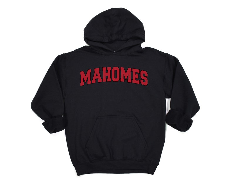 May include: Black hooded sweatshirt with the name "MAHOMES" in red, arched lettering across the chest. The sweatshirt has a front pocket and a drawstring hood. The sleeves are cuffed.