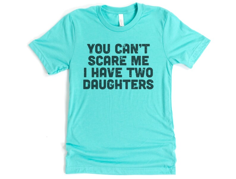May include: A turquoise blue t-shirt with the text "You can't scare me I have two daughters" printed in black.