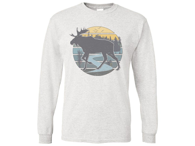 May include: A gray long-sleeve t-shirt with a vintage-style graphic of a moose walking through a forest with a river and a sunset in the background.