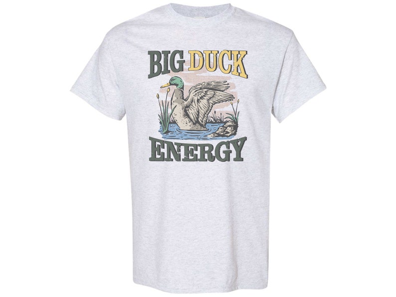 May include: A light grey t-shirt with a graphic of a duck in a pond and the text "BIG DUCK ENERGY".