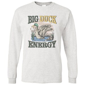 May include: A gray long-sleeve t-shirt with a vintage-style graphic of a duck in a pond. The text "BIG DUCK ENERGY" is printed in yellow and green letters.