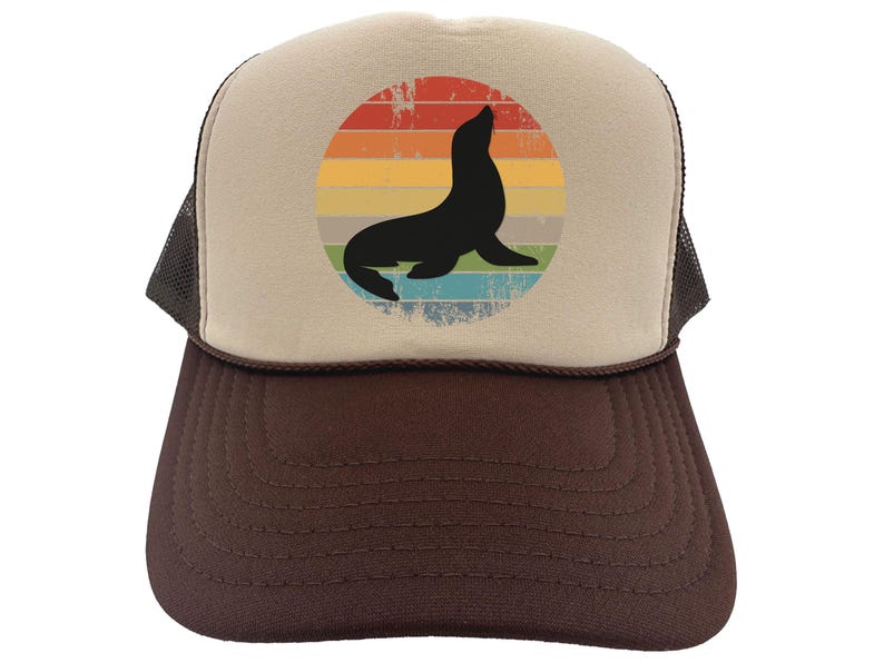 May include: A brown and beige trucker hat with a vintage-style graphic of a seal in a rainbow sunset. The hat has a mesh back.