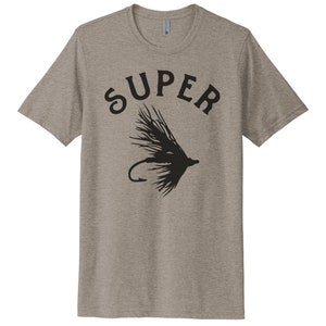 K&ouml;nnte beinhalten: Ein heidefarbenes T-Shirt mit einer schwarzen Grafik eines Fliegenfisch-K&ouml;ders und dem Wort "SUPER" dar&uuml;ber.
