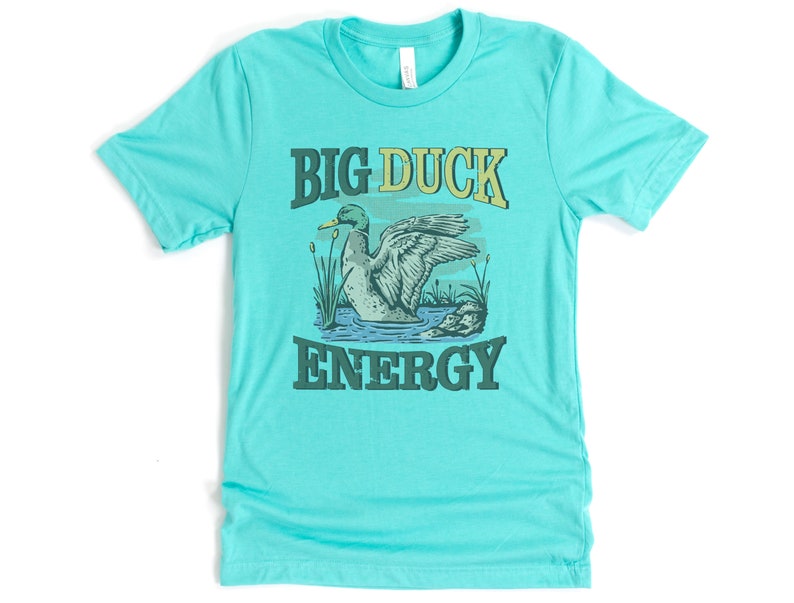 May include: A turquoise blue t-shirt with a green duck illustration and the text "BIG DUCK ENERGY" in a vintage style font.
