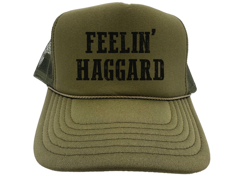 May include: A green trucker hat with a black mesh back. The front of the hat has the text "FEELIN' HAGGARD" in black.