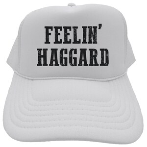 May include: White trucker hat with black text that reads "Feelin' Haggard".