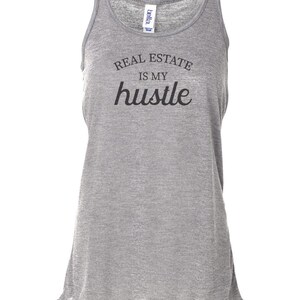 May include: Gray tank top with the text "REAL ESTATE IS MY hustle" printed in black.