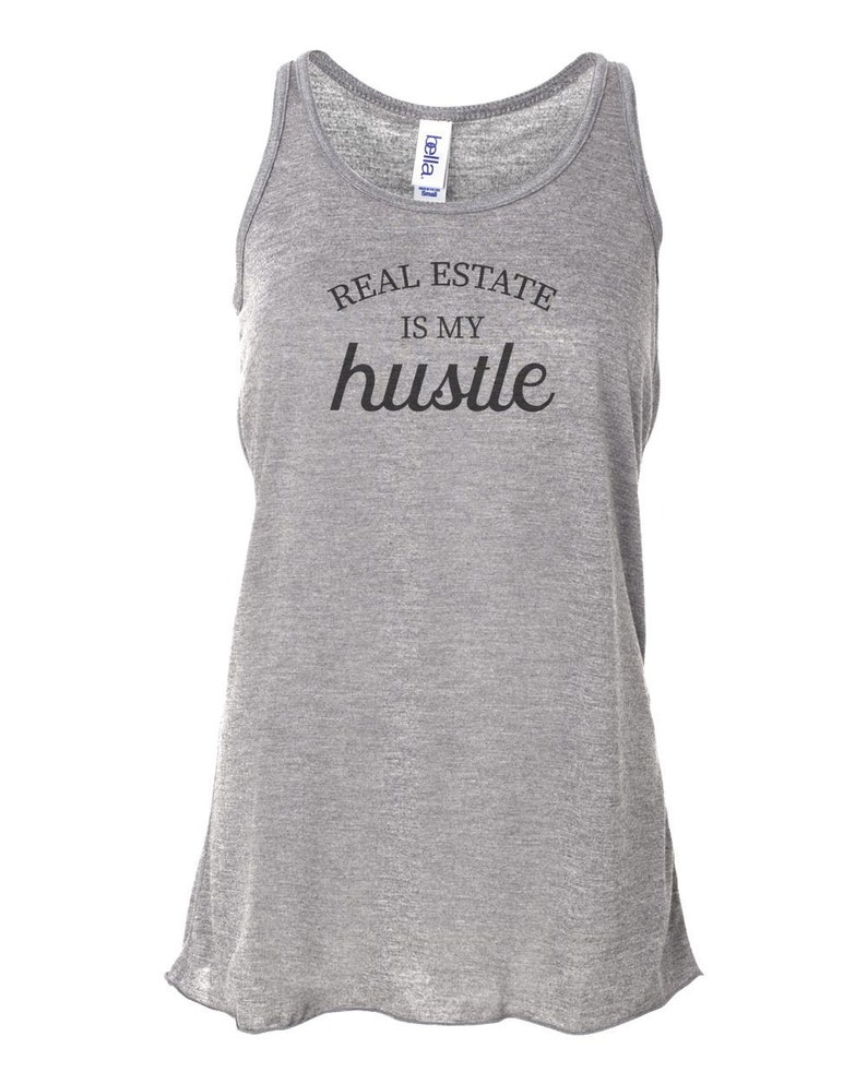 May include: Gray tank top with the text "REAL ESTATE IS MY hustle" printed in black.