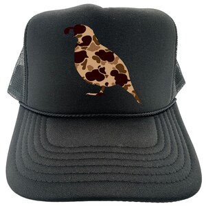 May include: Black trucker hat with a camouflage quail design. The hat has a mesh back and a black brim.