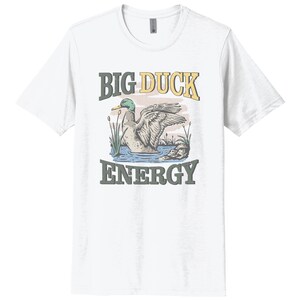 May include: White t-shirt with a cartoon duck illustration and the text "BIG DUCK ENERGY" in yellow and green.