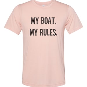 Puede incluir: Una camiseta rosa con el texto "MY BOAT. MY RULES." impreso en negro.