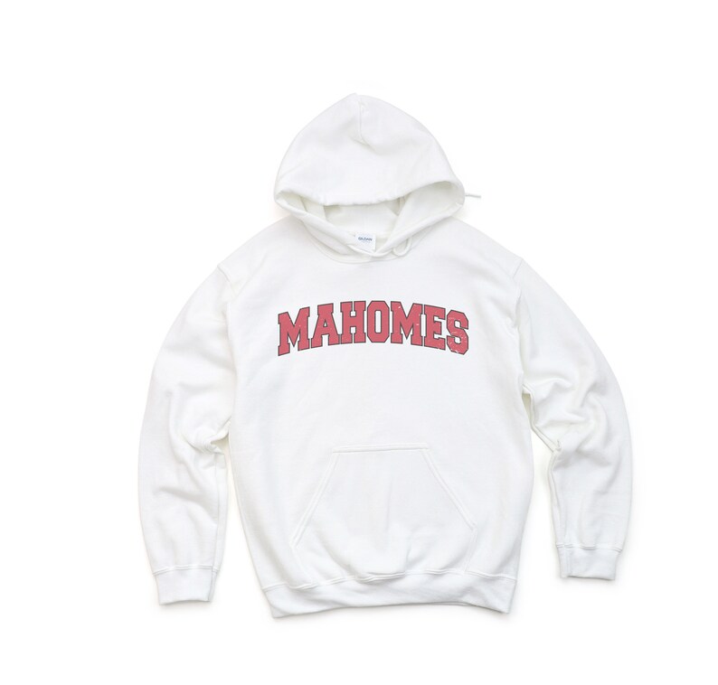May include: White hooded sweatshirt with the word "MAHOMES" in red block letters across the chest. The sweatshirt has a front pocket and a drawstring hood. The fabric appears to be a soft, comfortable material.