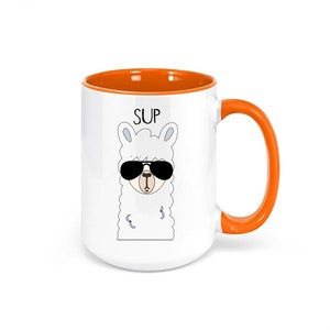 May include: White ceramic mug with an orange interior and handle. The mug features a cartoon llama wearing sunglasses, with the word "SUP" above it. A fun and quirky design for coffee or tea.