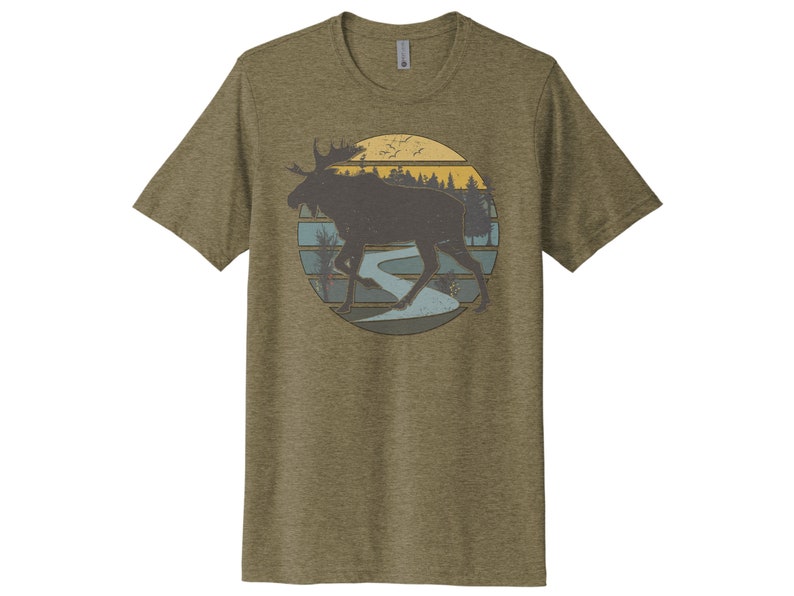 May include: A green t-shirt with a vintage-style graphic of a moose walking through a forest with a river and sunset in the background.