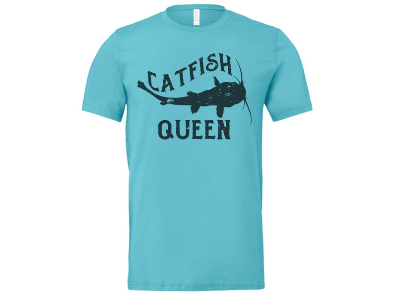 May include: A turquoise blue t-shirt featuring a black silhouette of a catfish and the text "Catfish Queen".