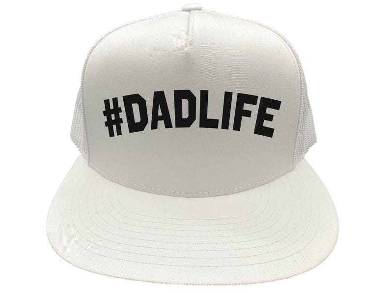 May include: White trucker hat with a curved brim and mesh back. The hat features the text "#DADLIFE" in bold, black letters across the front. A casual accessory for everyday wear.