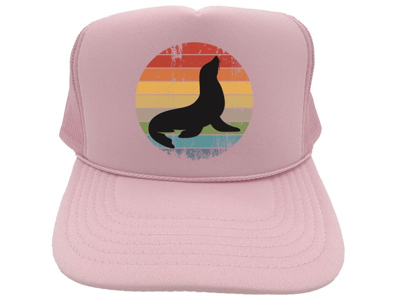 May include: Pink trucker hat with a retro-style graphic of a seal in front of a rainbow. The seal is black and the rainbow is in shades of yellow, orange, red, blue, and green.