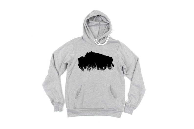 May include: A light gray hoodie with a black graphic of a bison. The hoodie has a drawstring hood, a front pocket, and long sleeves. The bison graphic is a silhouette with a textured, grassy base.