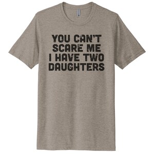 May include: A heather grey t-shirt with the text "You can't scare me I have two daughters" printed in black.