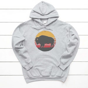 May include: A gray hooded sweatshirt with a vintage-style graphic of a black silhouette of a buffalo in front of a yellow, orange, and red sunset.