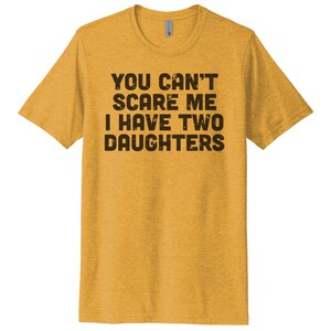May include: A yellow t-shirt with the text "YOU CAN'T SCARE ME I HAVE TWO DAUGHTERS" printed in black.
