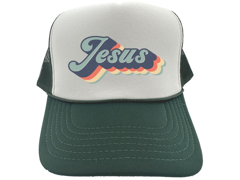 Puede incluir: Una gorra de camionero blanca y verde con un gr&aacute;fico retro de "Jes&uacute;s" en azul, naranja, amarillo y rojo.
