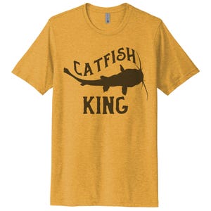 May include: A yellow t-shirt with a brown catfish silhouette and the text "CATFISH KING" printed on the front.