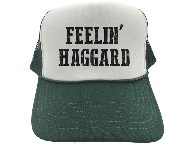 May include: White and green trucker hat with black text that reads "Feelin' Haggard".