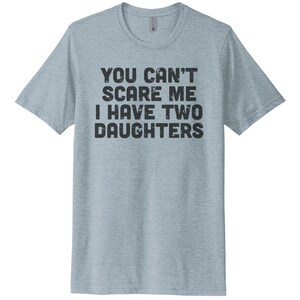 May include: A light blue t-shirt with the text "You can't scare me I have two daughters" in black.
